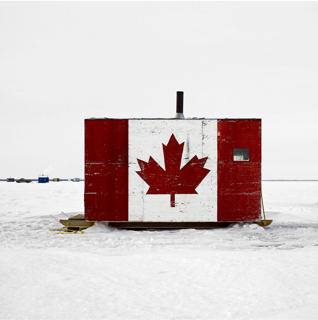 An ice fishing hut that has been painted like a Canadian flag.