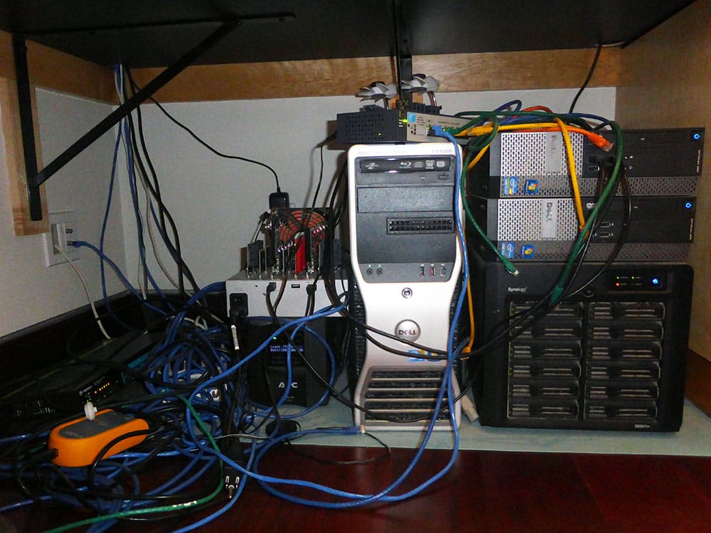 A computer, storage array and a bunch of wires under a desk.