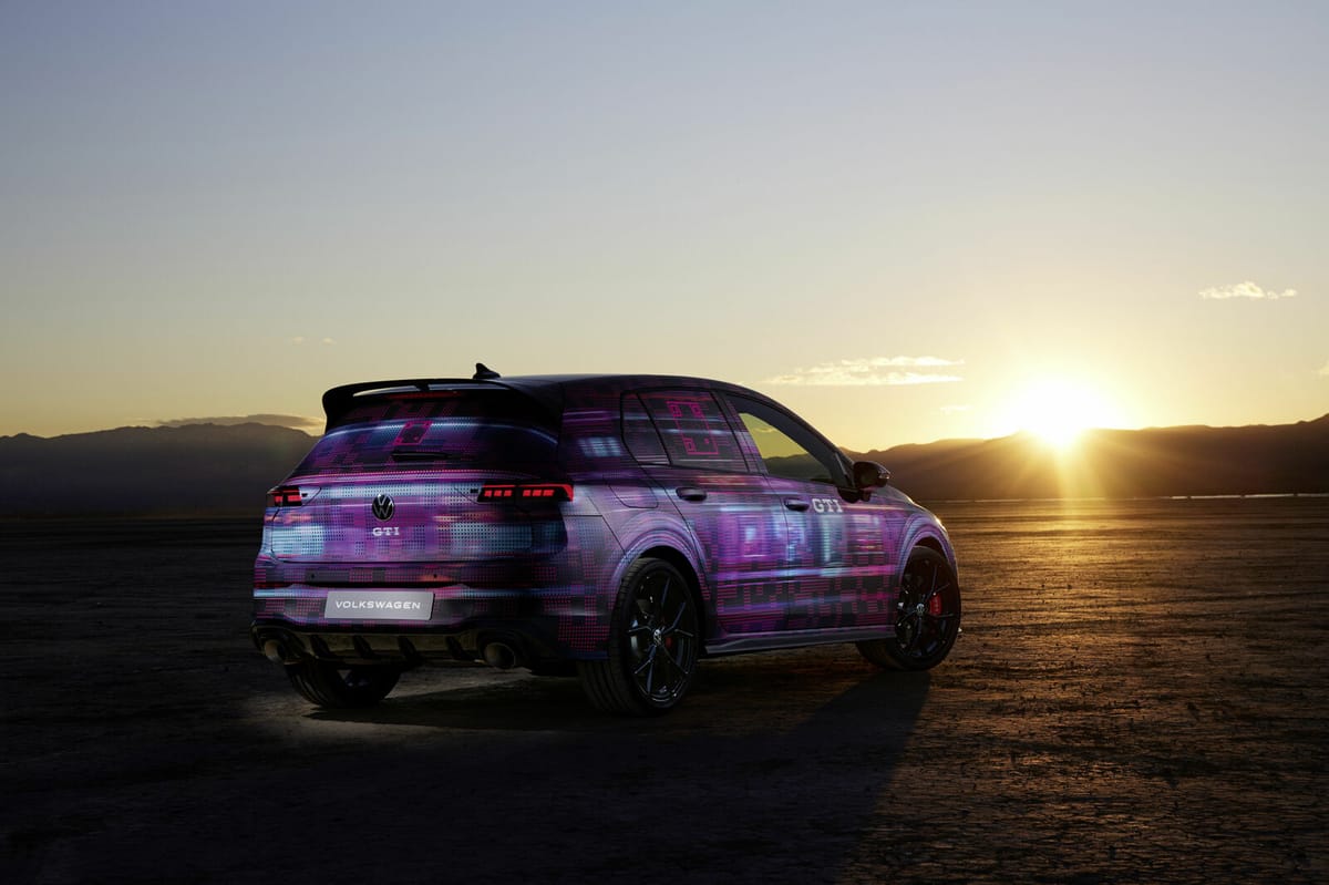 A Volkswagen Golf with purple camo paint at sunset.